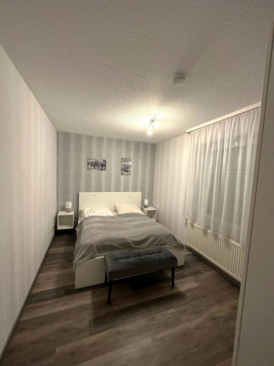 Schlafzimmer mit Bett, Nachttischen und Fenster mit Vorhängen.