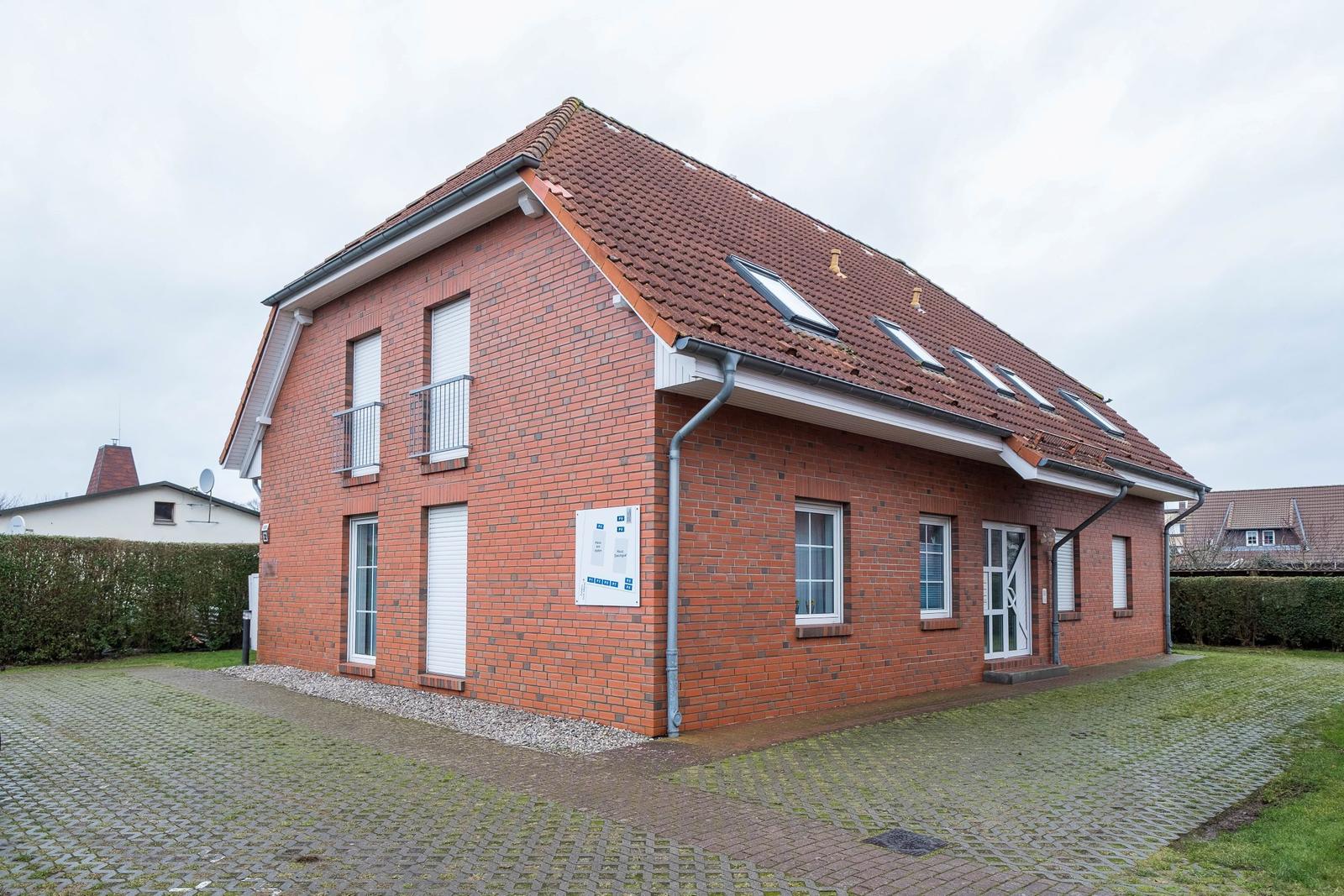 Rotes Backsteinhaus mit Dachfenstern und gepflastertem Hof.