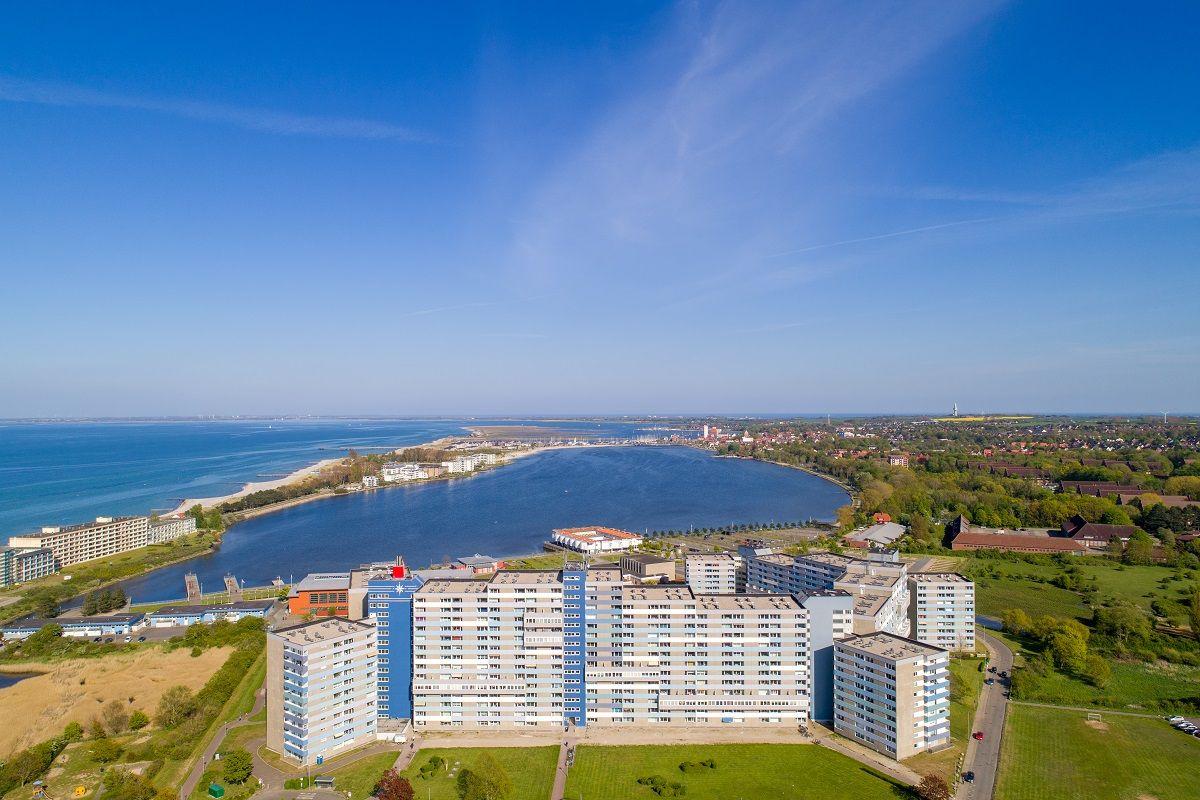 Aerial view of apartment complex near coastal waterway and green areas.