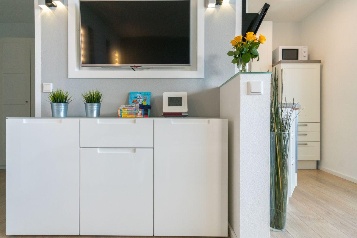 Wohnbereich mit Fernseher, weißen Schränken und Pflanzen.