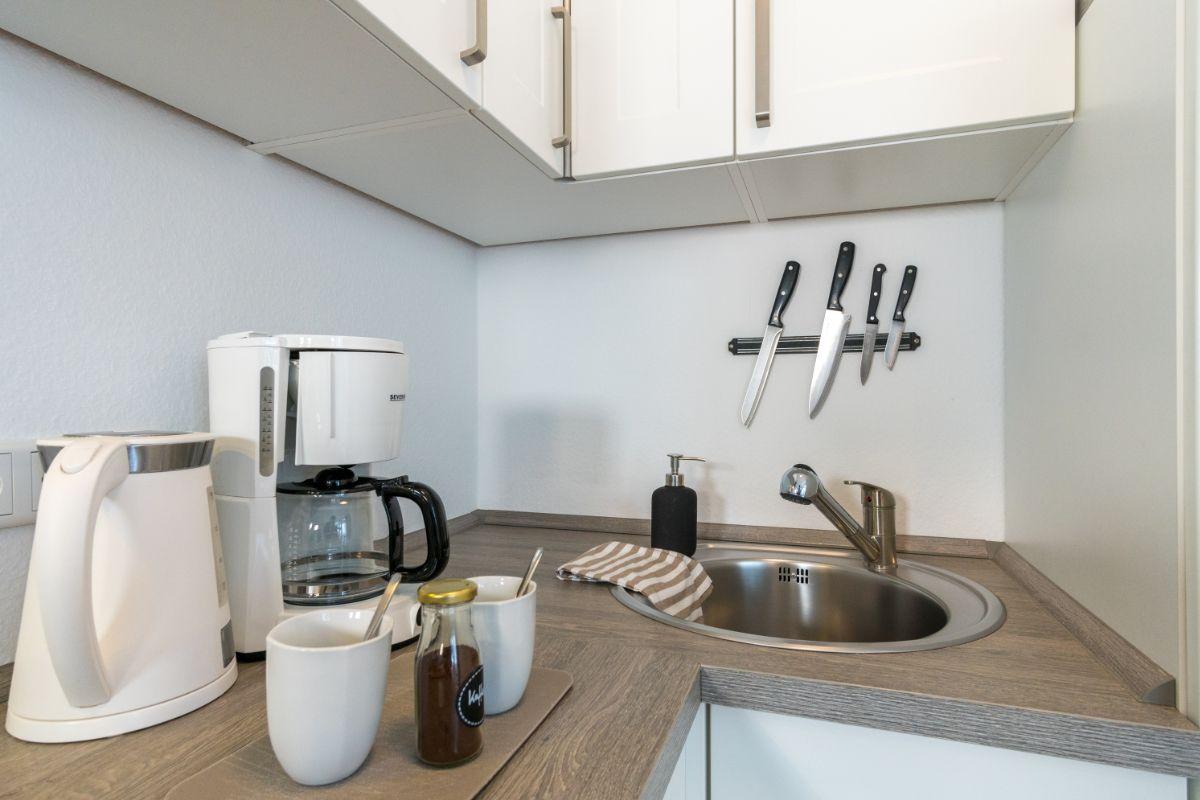 Küchenbereich mit Spüle, Kaffeemaschine und Messerblock an der Wand.