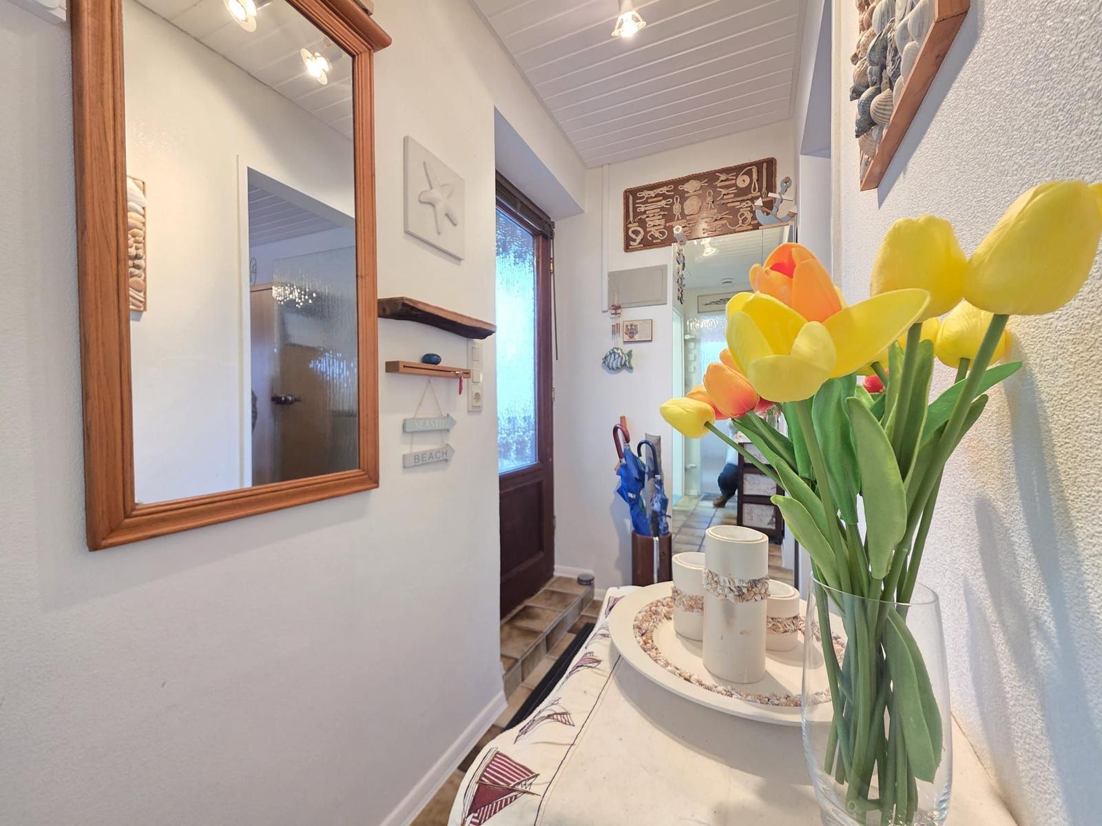 Hallway with mirror, flowers, and sea-themed decor on the walls.