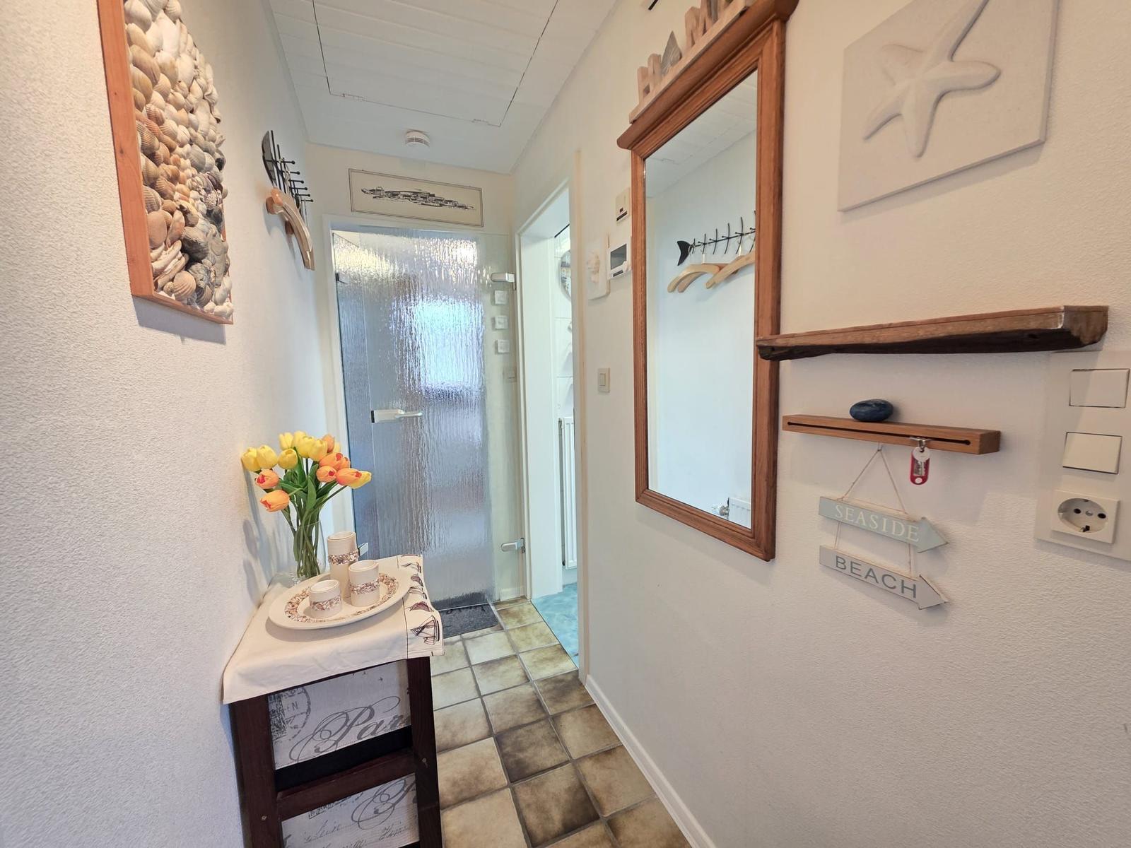 Hallway with mirror, wooden shelves, and seaside-themed wall decor.