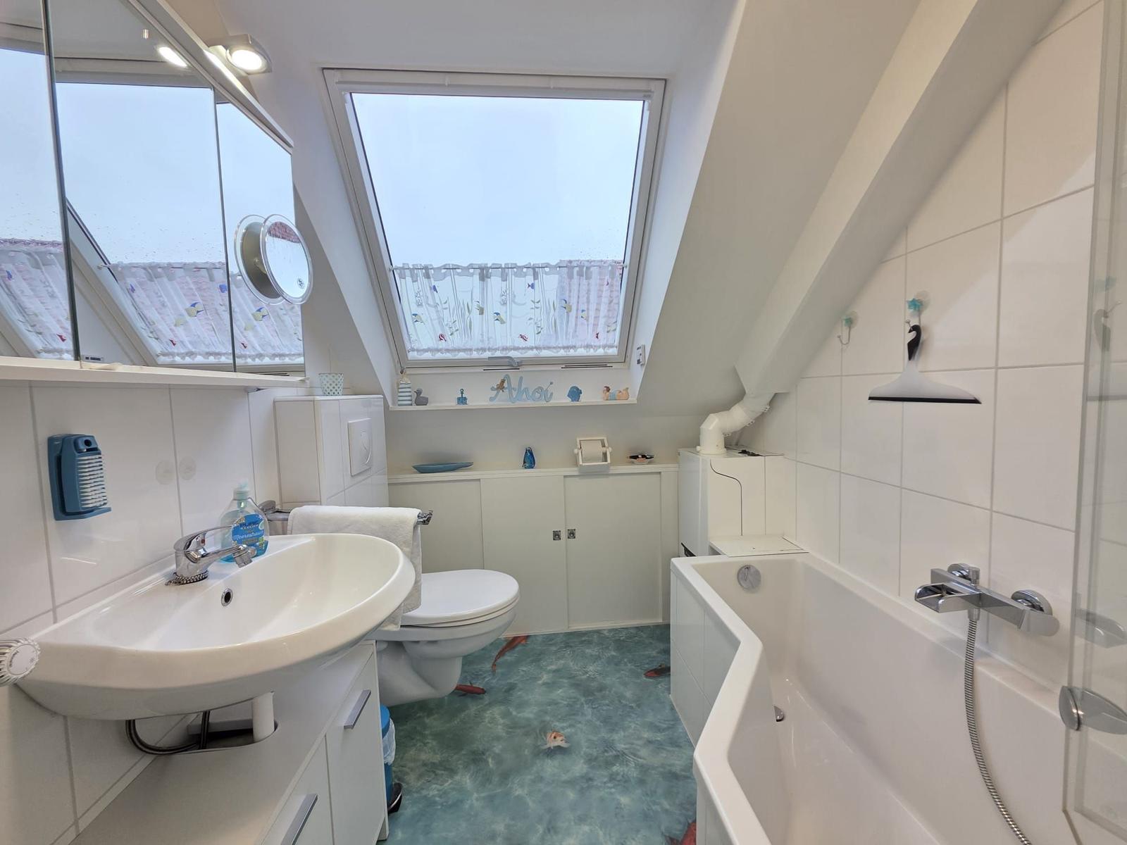 Bathroom with skylight, bathtub, and sink. Floor covering in sea design.