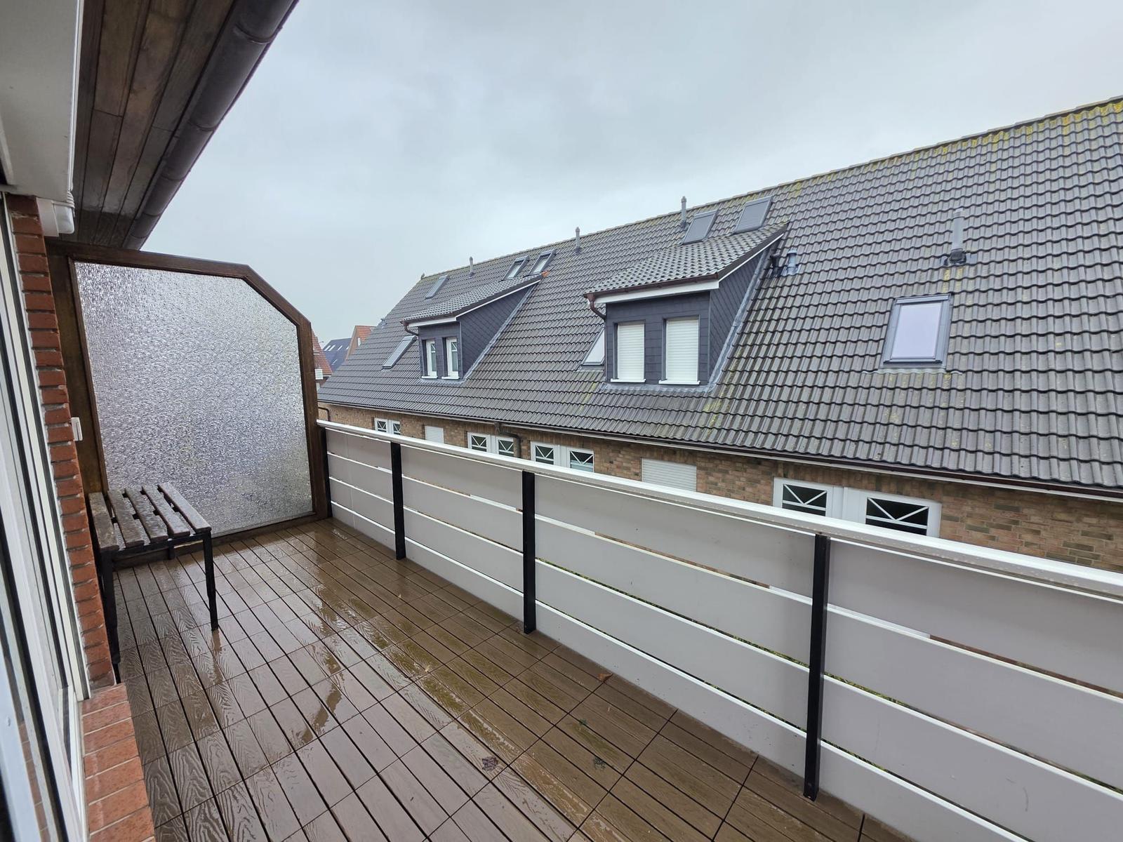 Terrace with wooden floor and bench. View of roof with skylights.