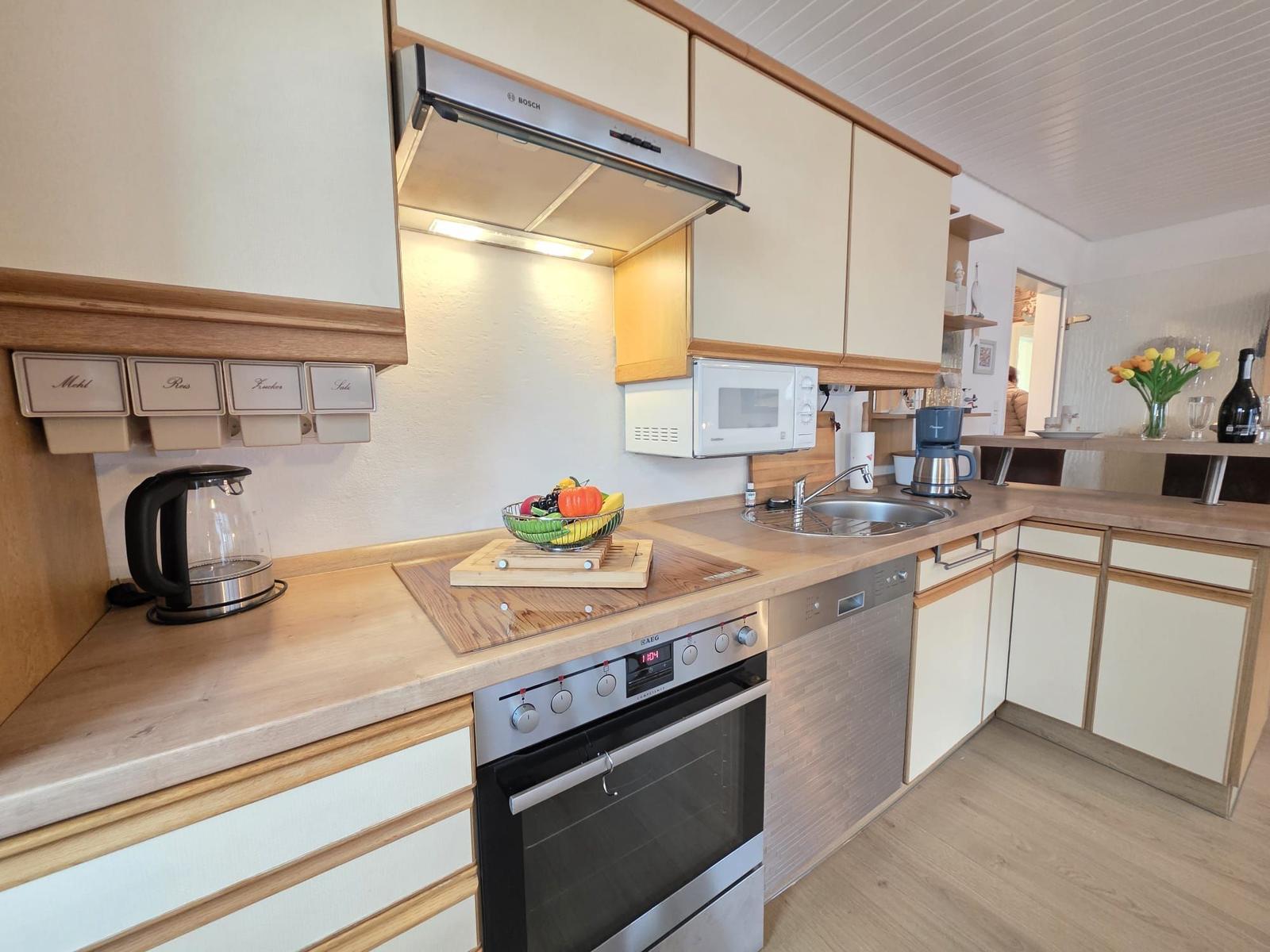 Kitchen with stove, sink, and microwave. Wooden surfaces and white cabinets.