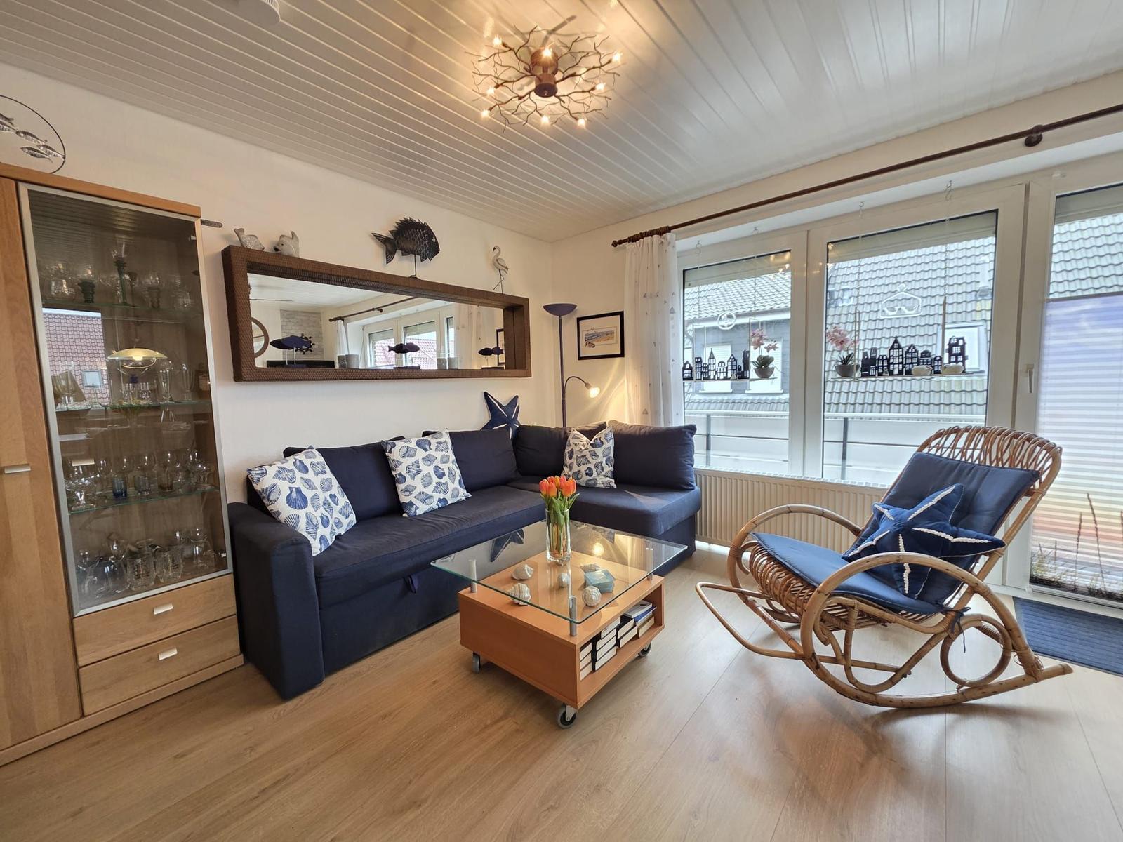 Living room with sofa, rocking chair, and glass wall. View to balcony with roof view.