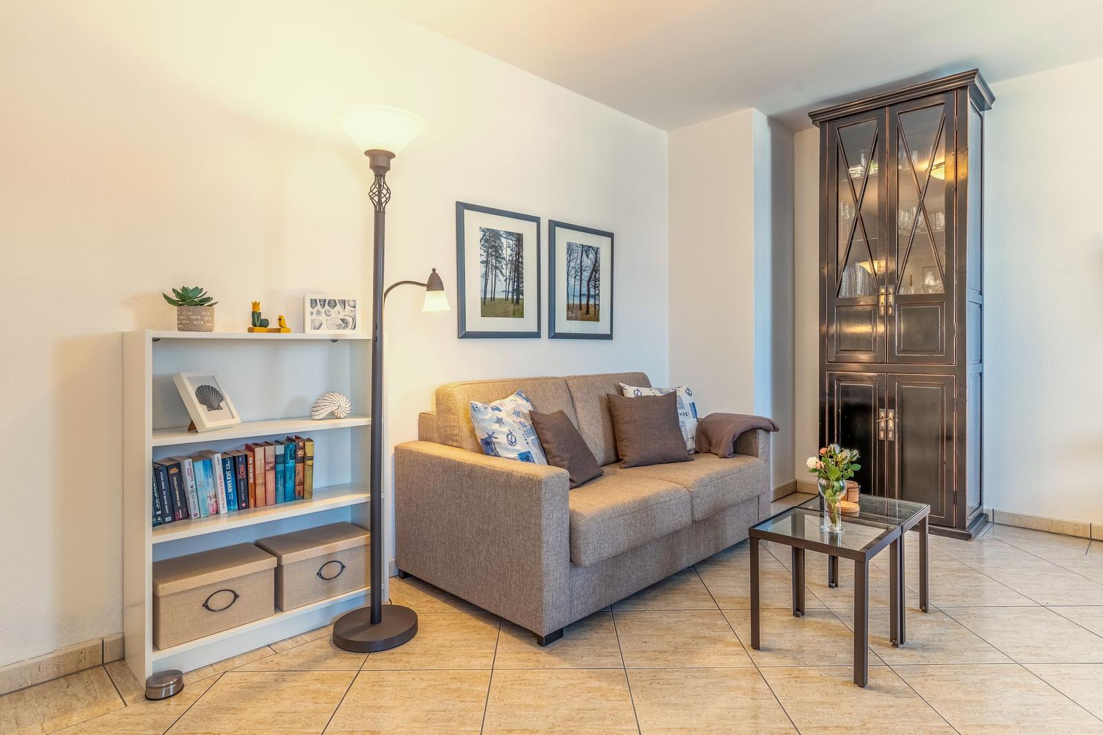 Ein Wohnzimmer mit Sofa, Beistelltisch, Bücherregal und Schrank.