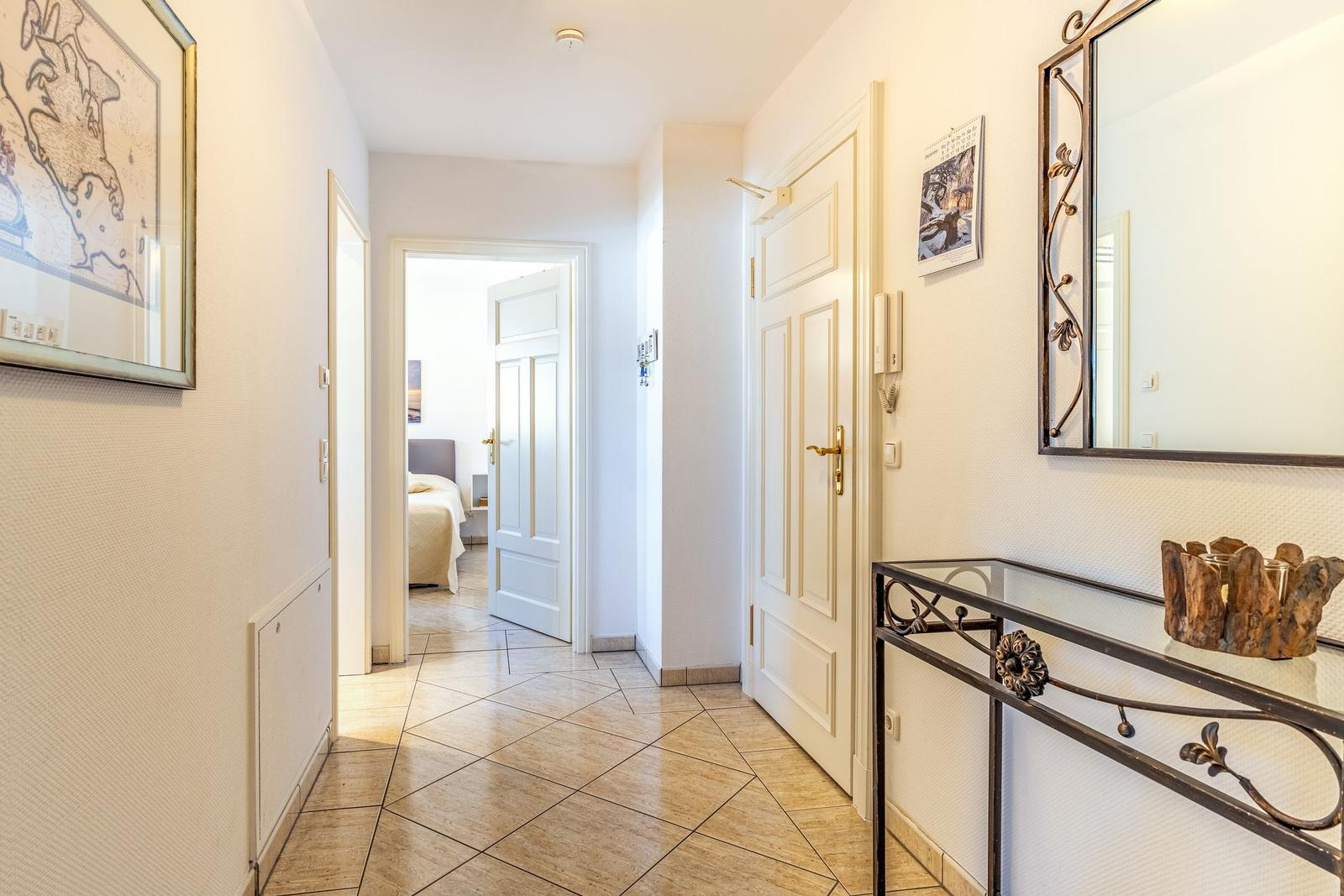 Flur mit Tür zu Schlafzimmer, Spiegel und Dekorationsstück.