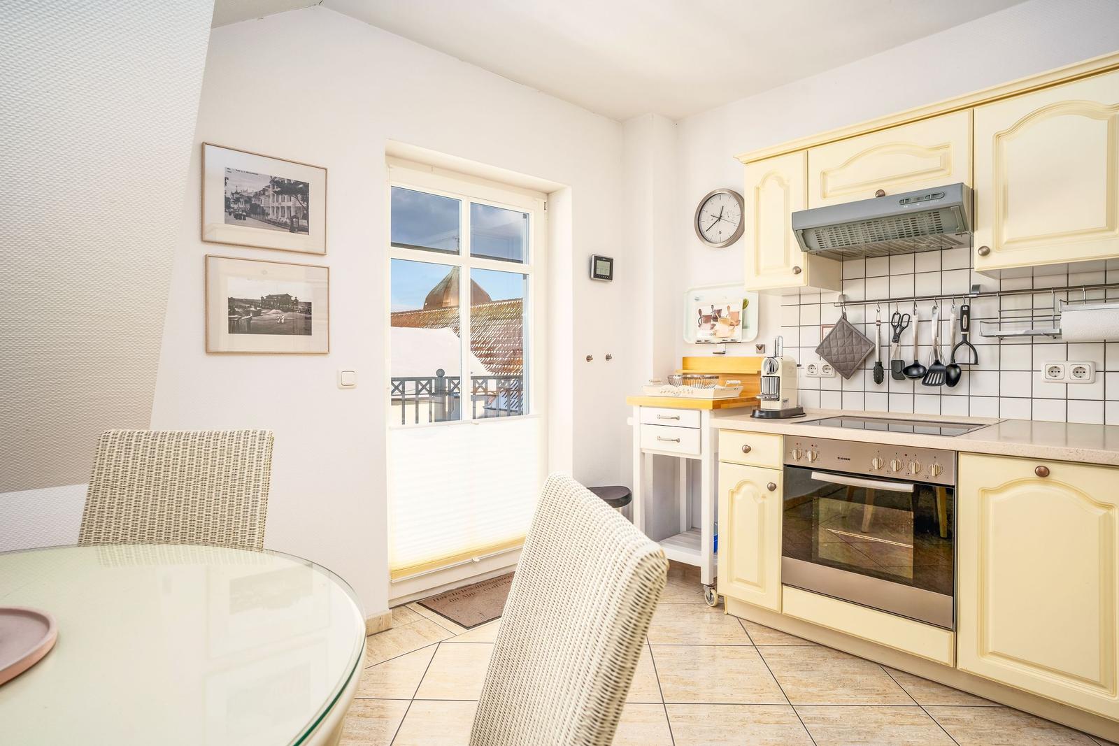 Küche mit Essbereich, Fenster zur Terrasse und Küchenzeile mit Dunstabzug.