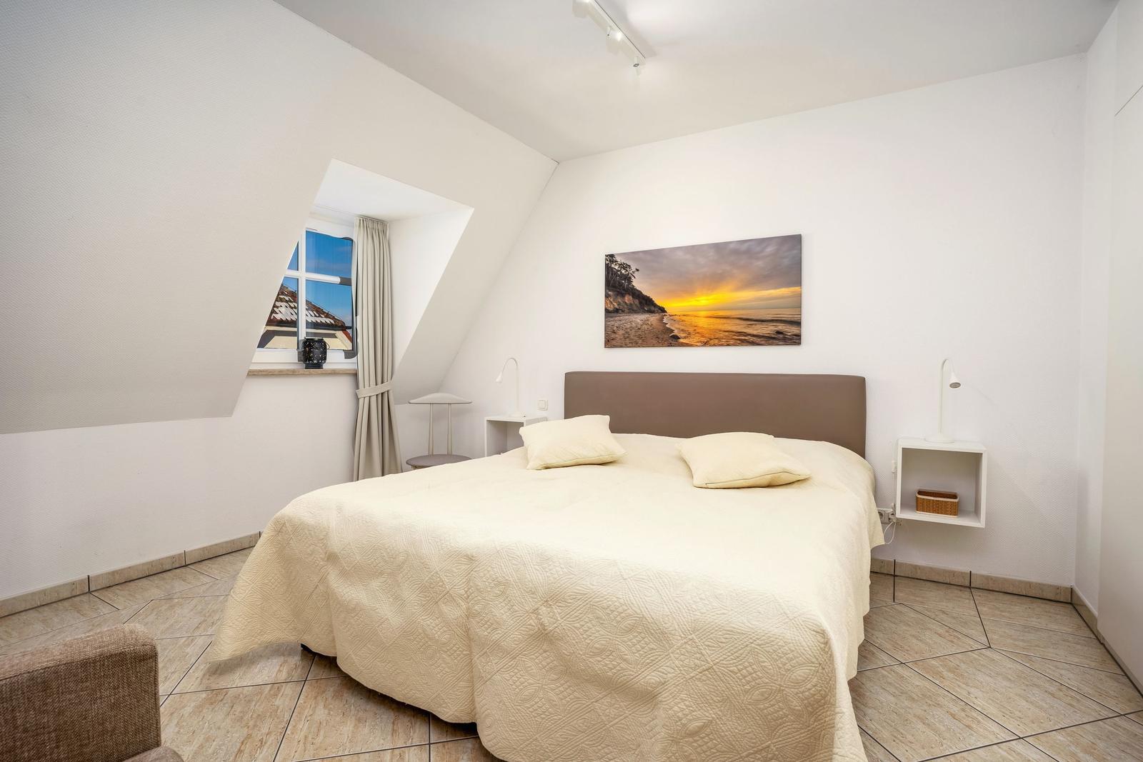 Schlafzimmer mit Dachfenster, Bett und Wandbild an der Wand.