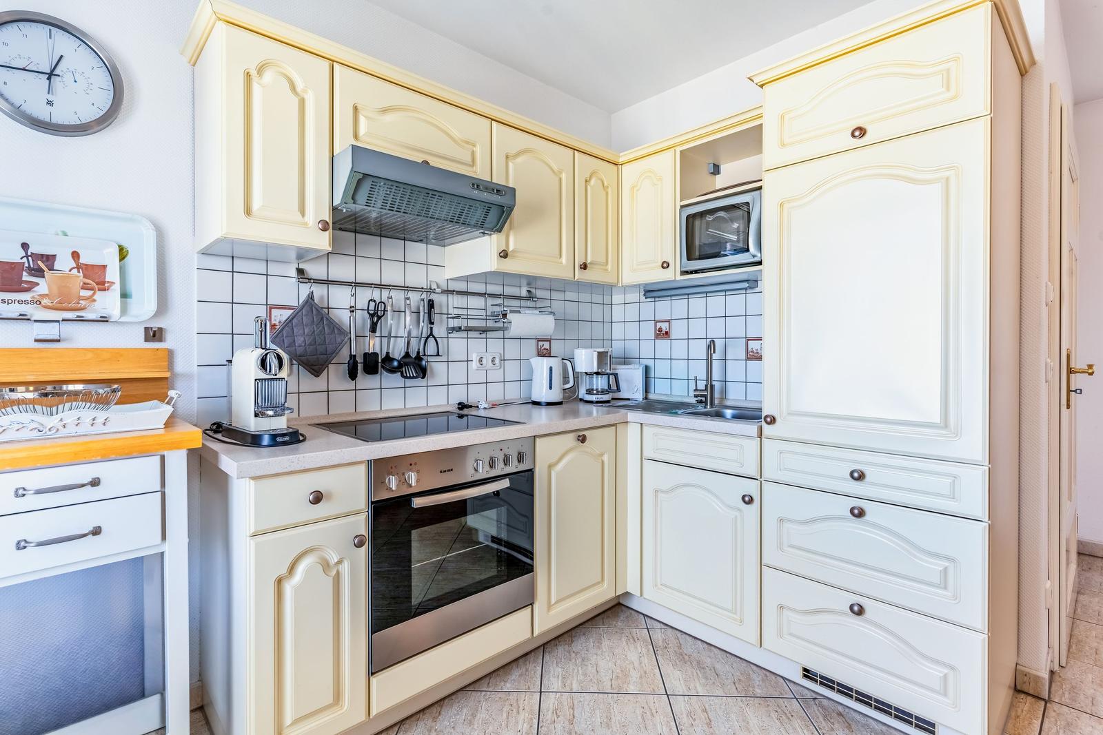 Küche mit cremefarbenen Schränken, Edelstahlherd und Mikrowelle.