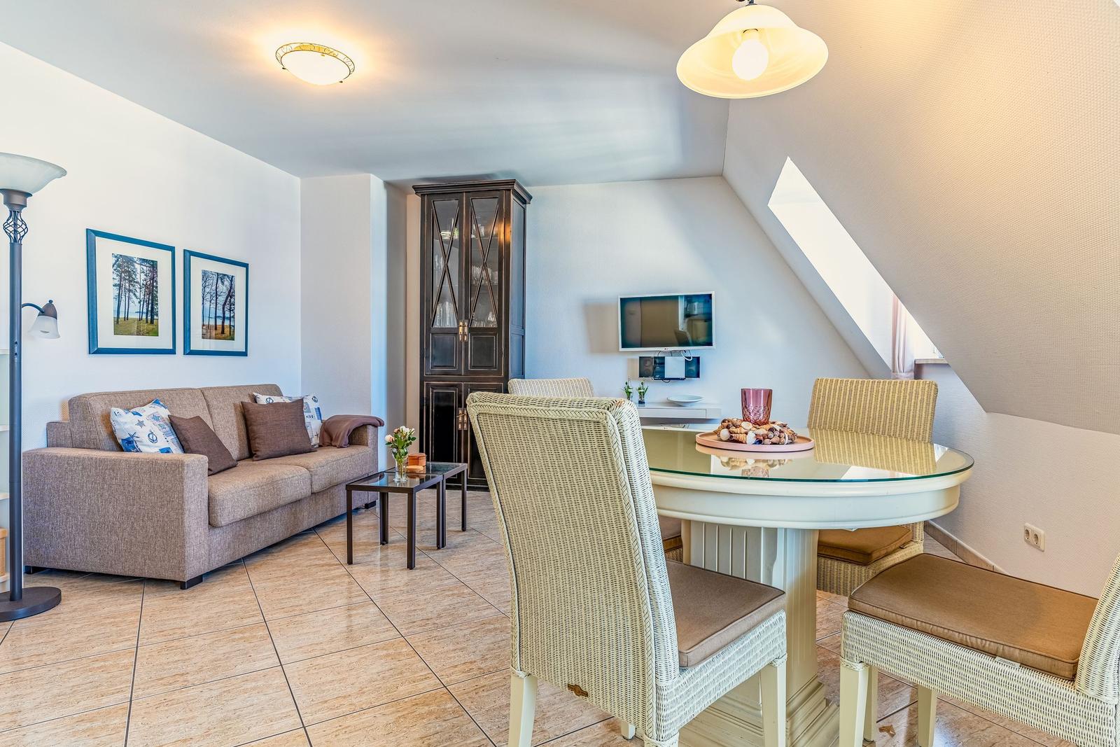 Wohn- und Essbereich mit Sofa, Esstisch und TV unter schrägen Dachschrägen.