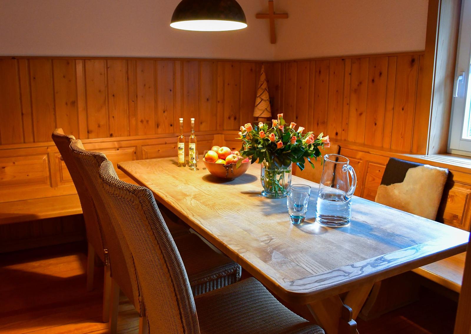Holztisch mit Stühlen, Blumen und Obst an der Wand