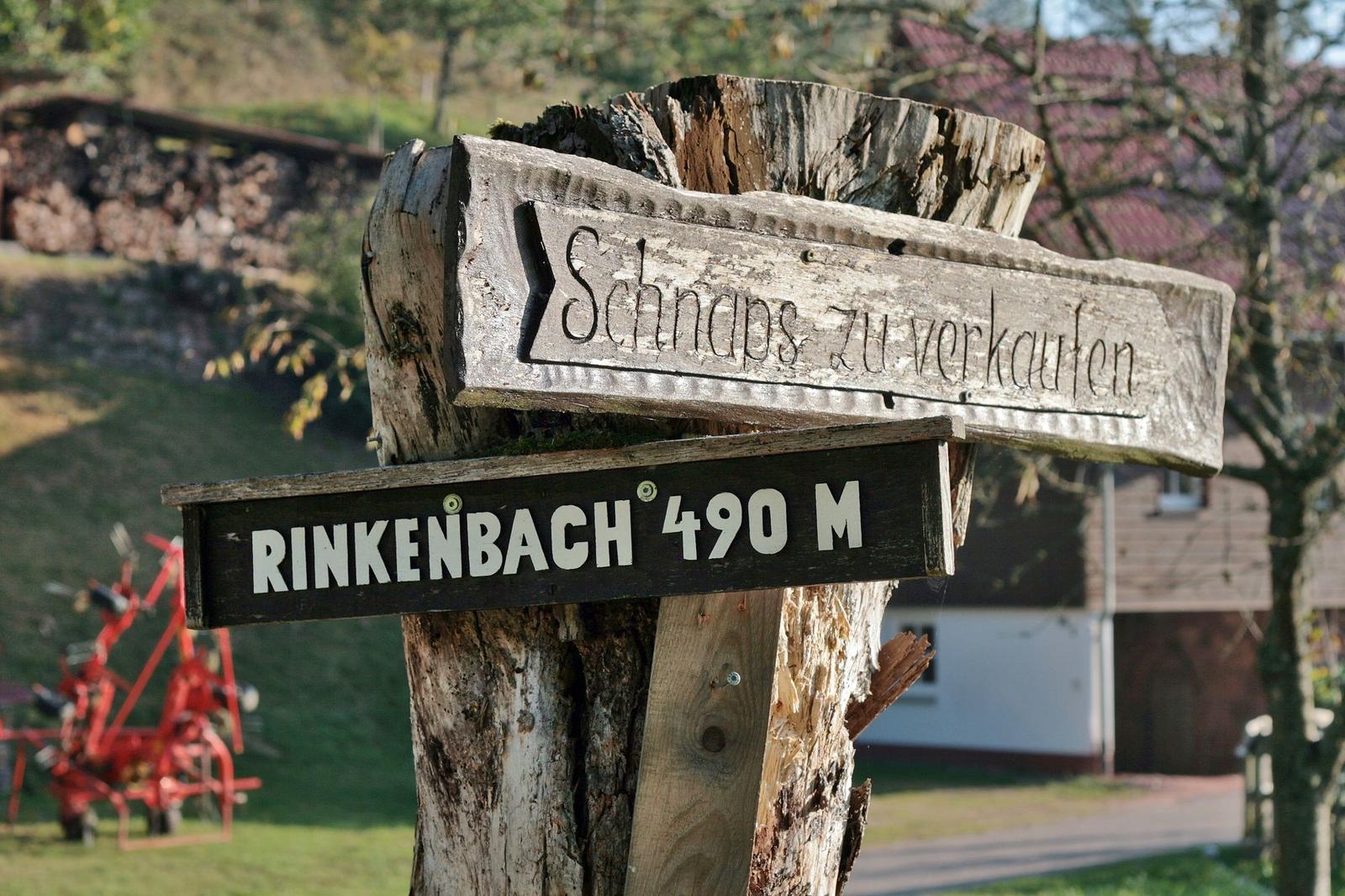 Holzschild weist auf Schnapsverkauf und Entfernung zu Rinkenbach hin.
