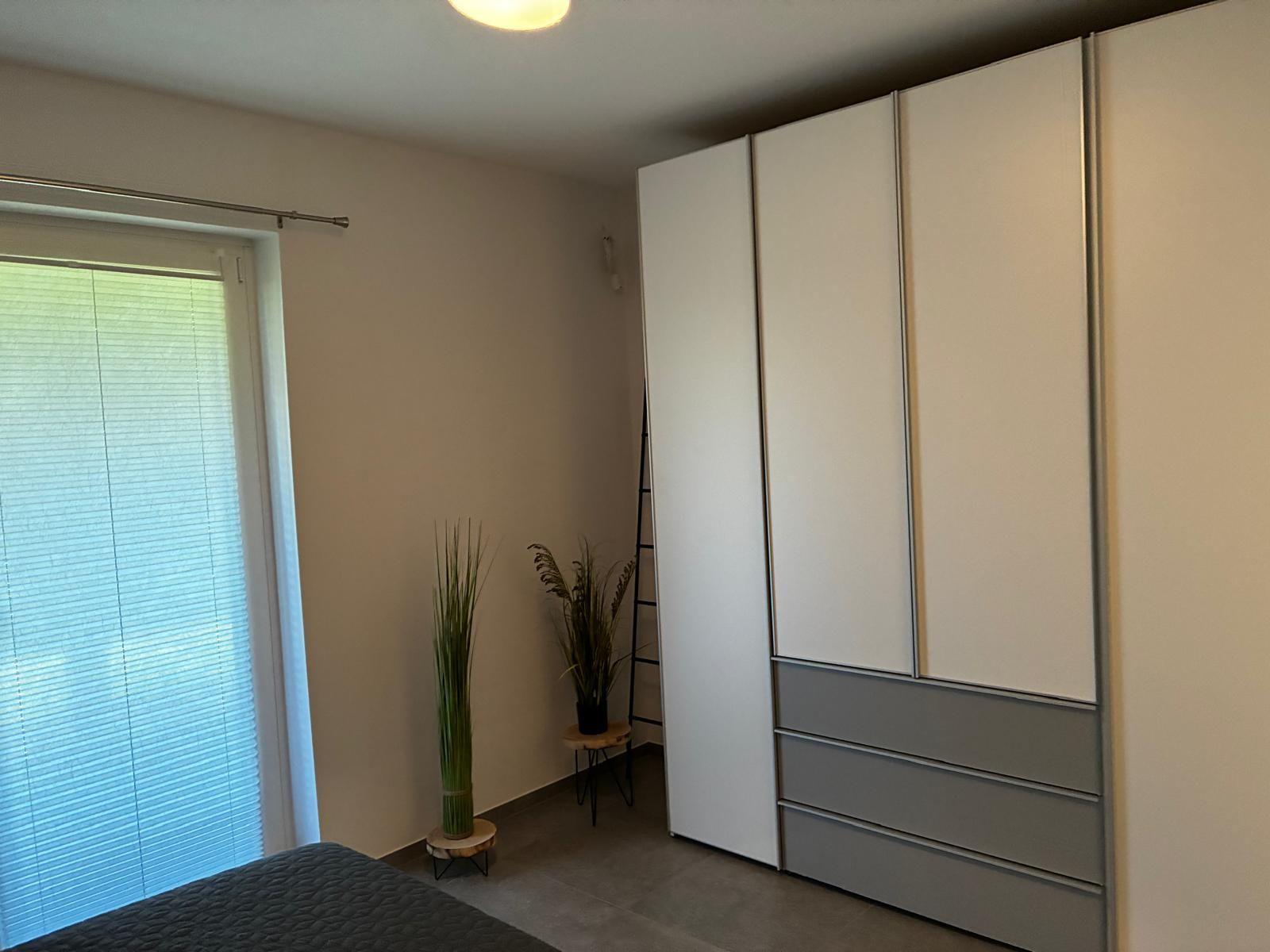 Schlafzimmer mit Kleiderschrank, Fenster und Pflanzen.