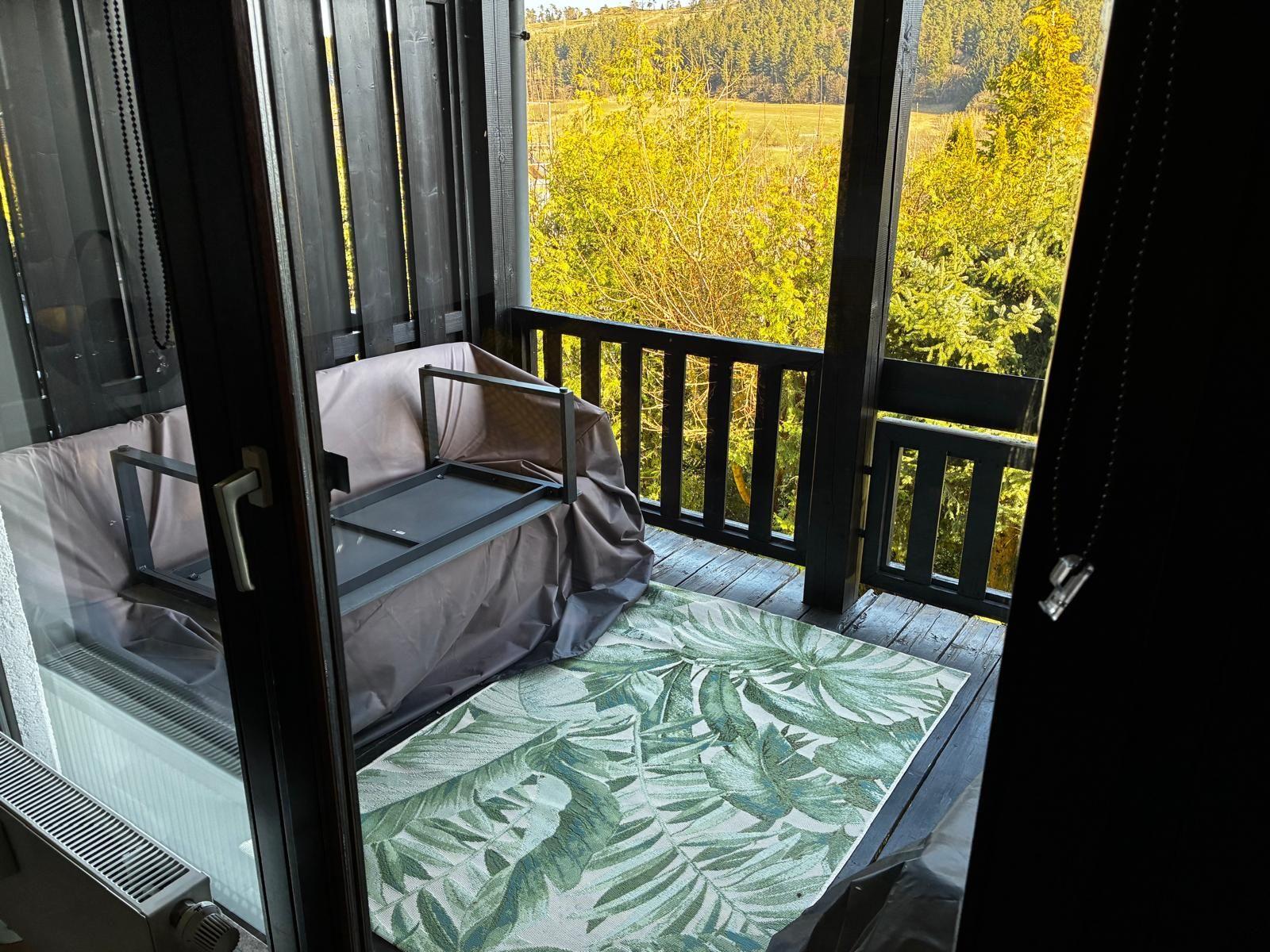 Terrasse mit Sitzmöbeln und Blick auf Wald und Feld