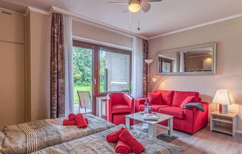 Zimmer mit rotem Sofa, Bett und Fenster zum Garten.