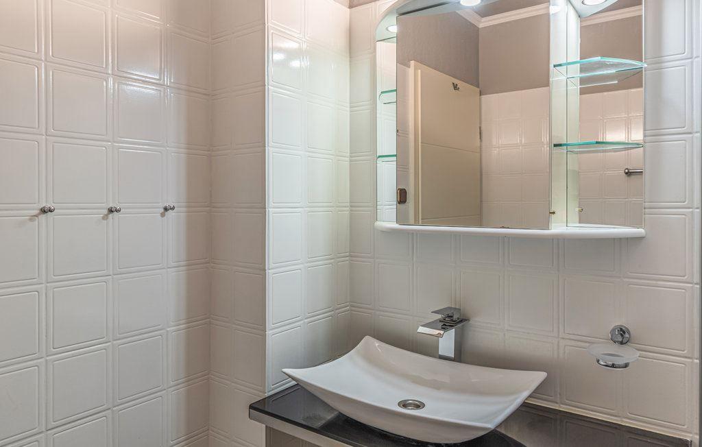 Badezimmer mit Waschbecken, Spiegel und Glasregalen an der Wand.