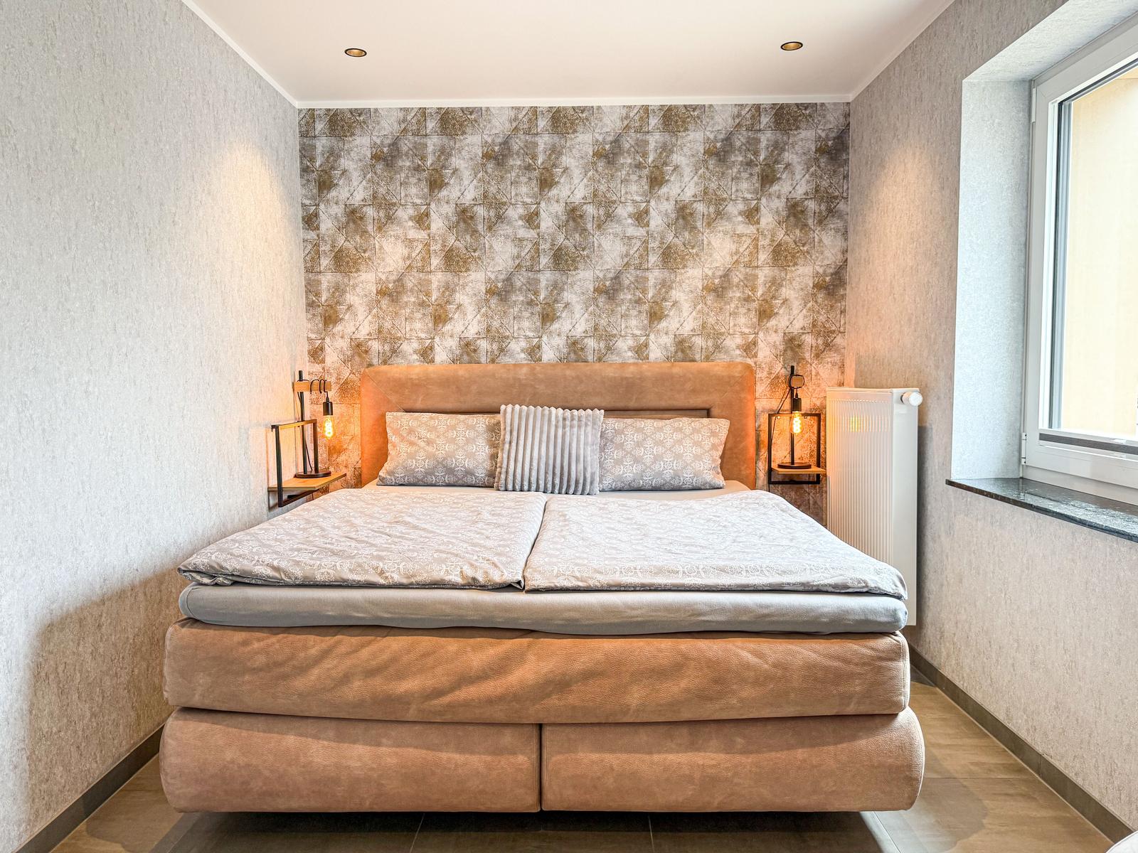 Schlafzimmer mit Bett, Wandverkleidung und Fenster.
