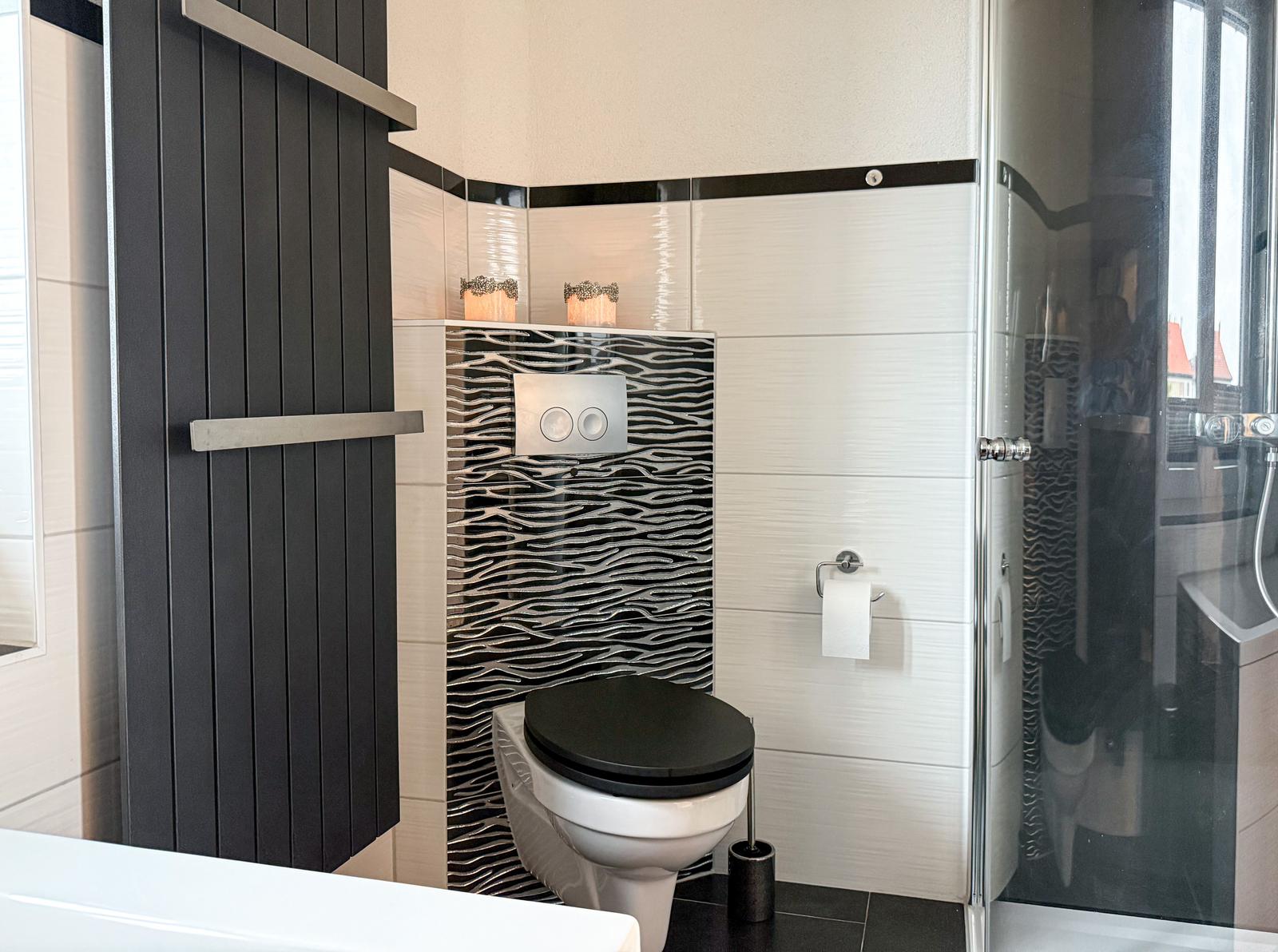 Bad mit Toilette, Dusche und schwarz-weißen Fliesen