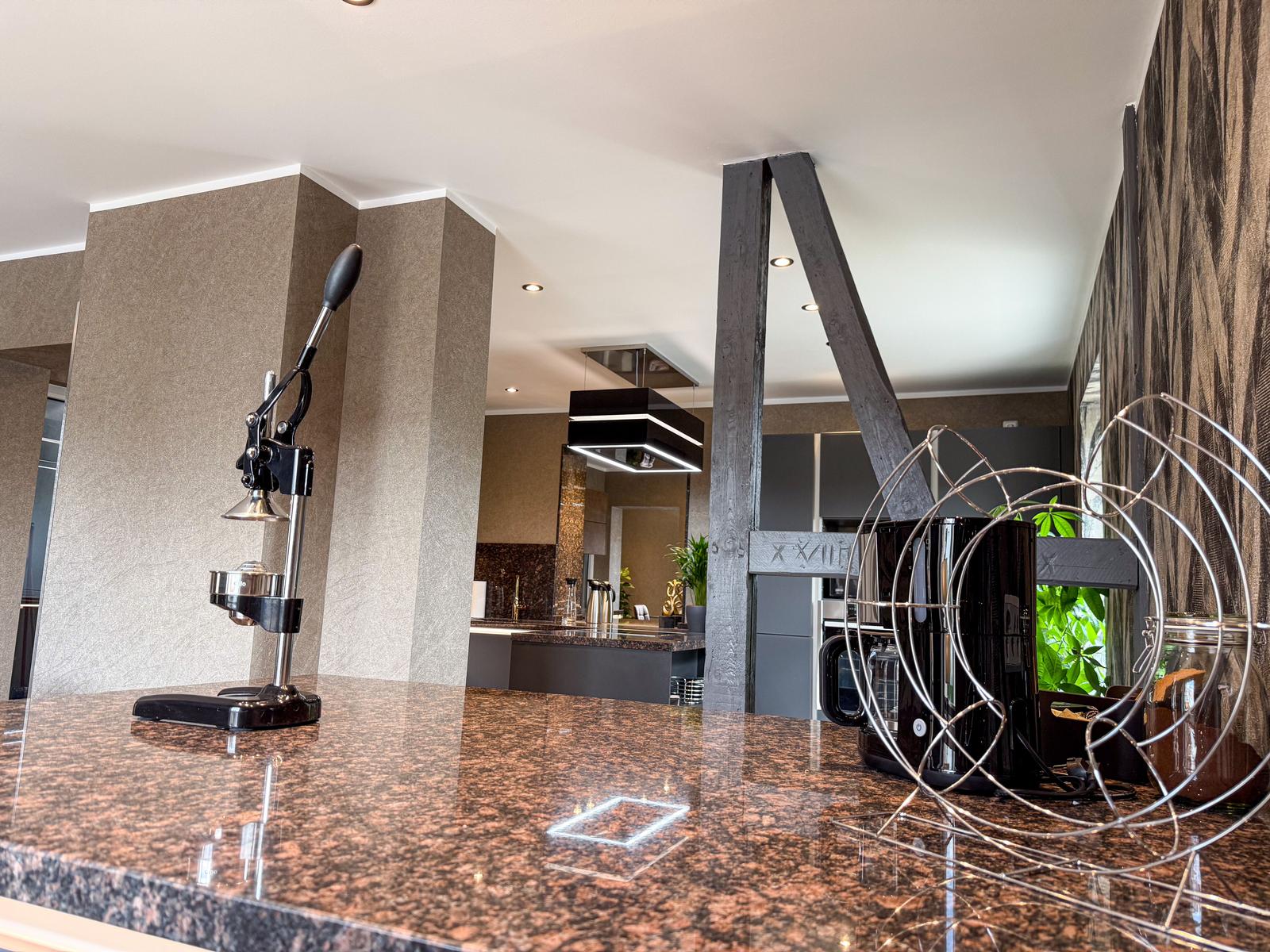 Küche mit Granitplatte, Kaffeemaschine und moderner Beleuchtung.