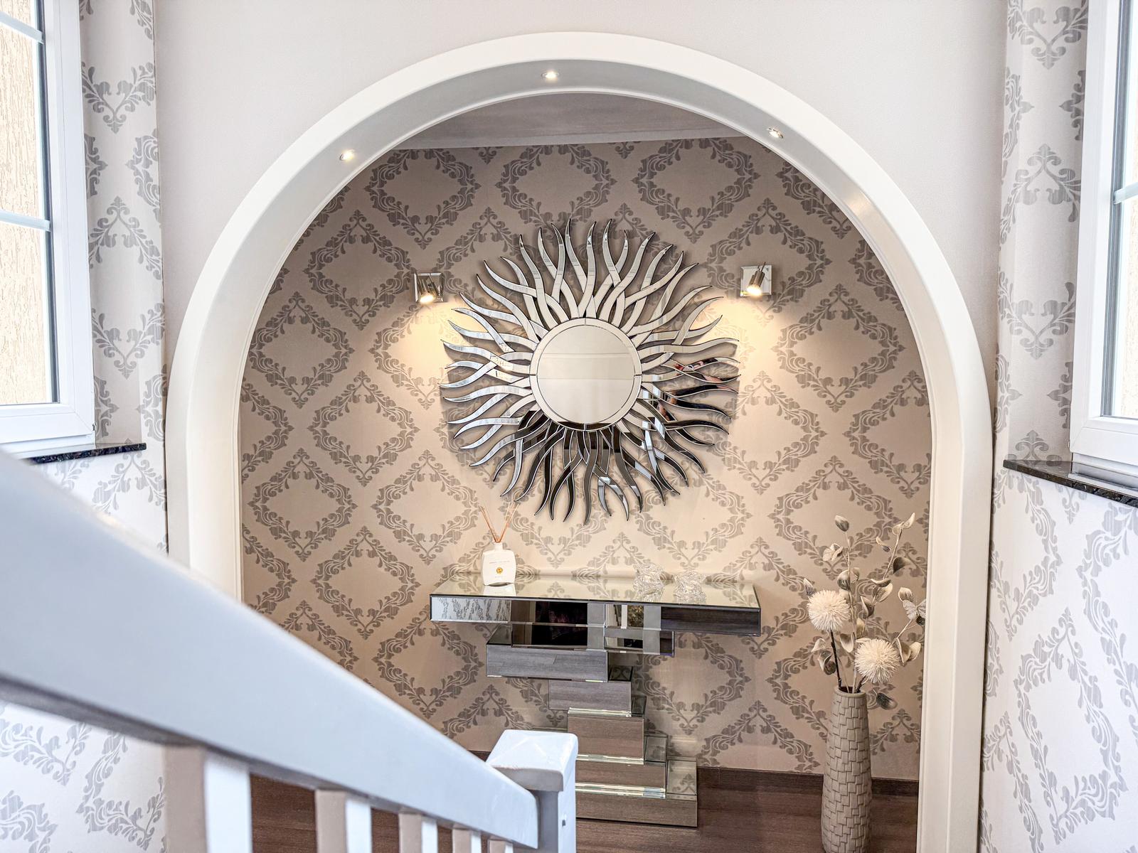 Eingangsbereich mit Bogen, Spiegelscheibe und dekorativer Wandtapete.