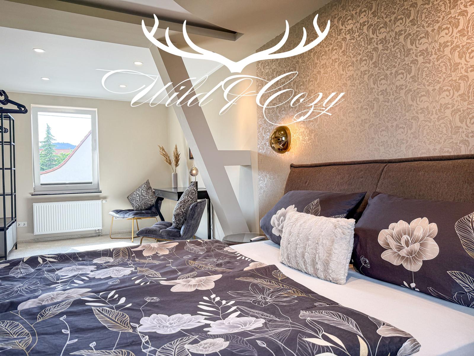 Schlafzimmer mit Bett, Fenster und Schreibtisch.