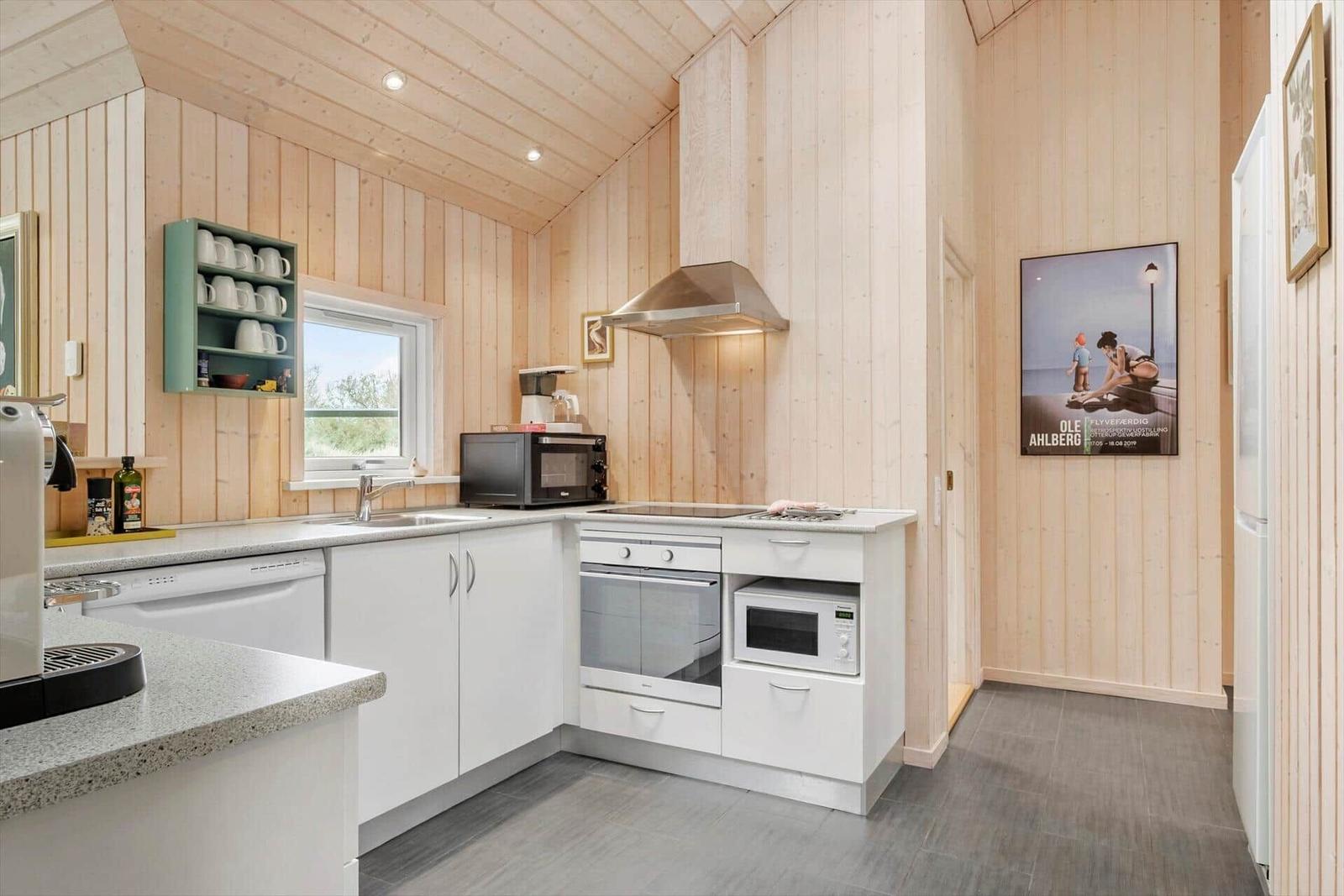 Kitchen with wooden walls, white cabinets, and modern equipment.