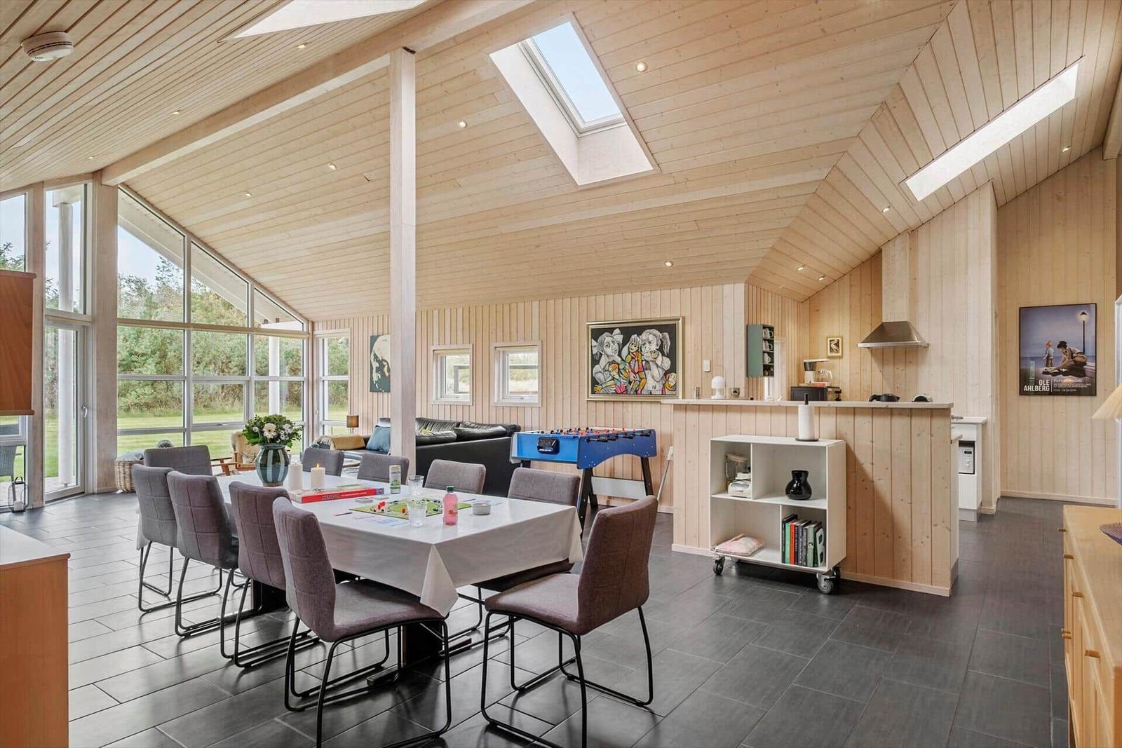 Large space with dining area, game table, and kitchen. Wooden ceiling and large windows.