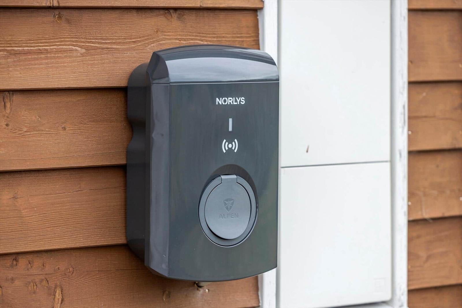 Outdoor electric vehicle charging point mounted on wooden wall