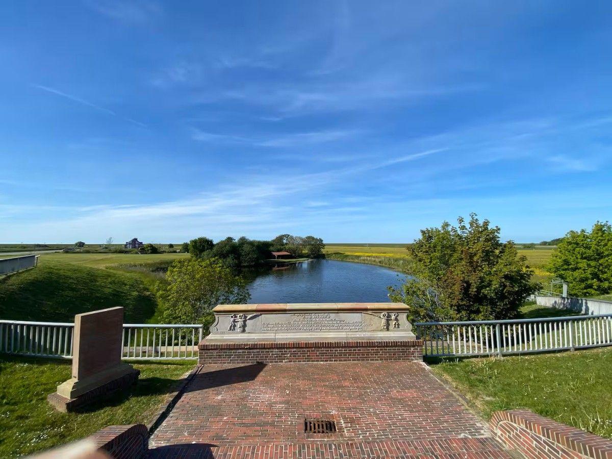 Quiet viewpoint with bridge, river, and green fields under blue sky.