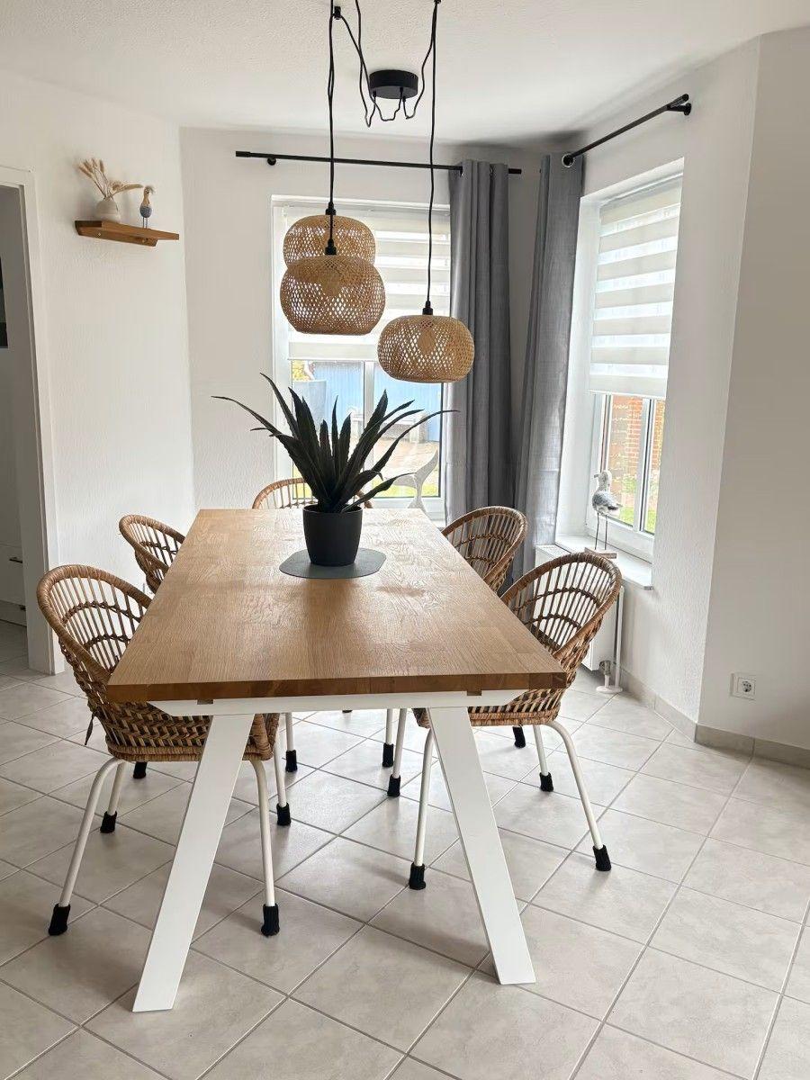 Dining room with wooden table, rattan chairs, and three pendant lamps.