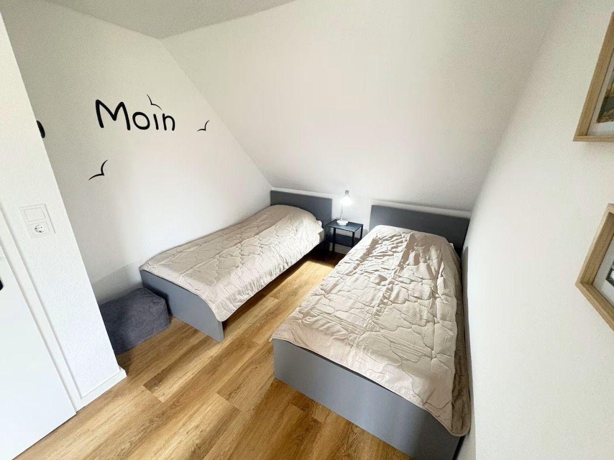 Two beds in an attic room with wooden floor and wall decoration.