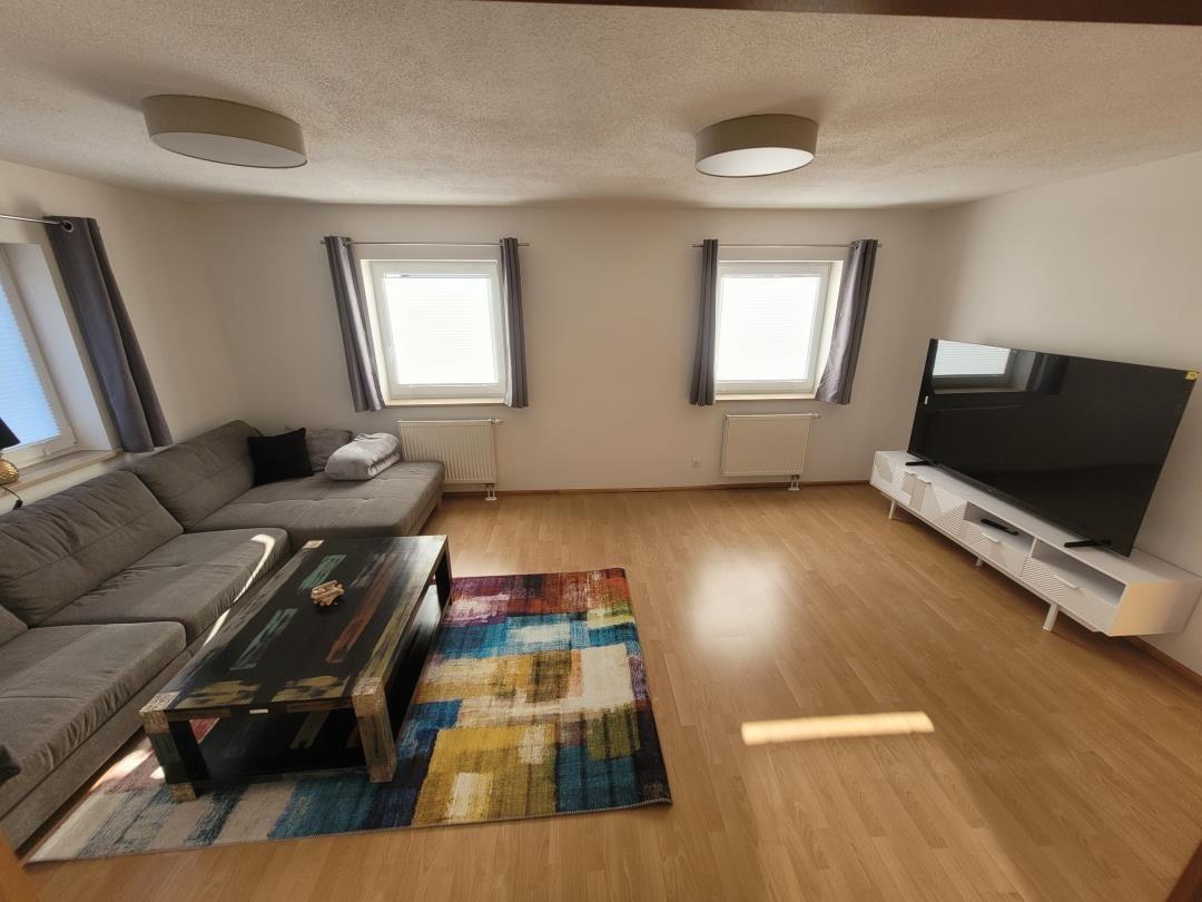 Living room with sofa, TV, and wooden floor