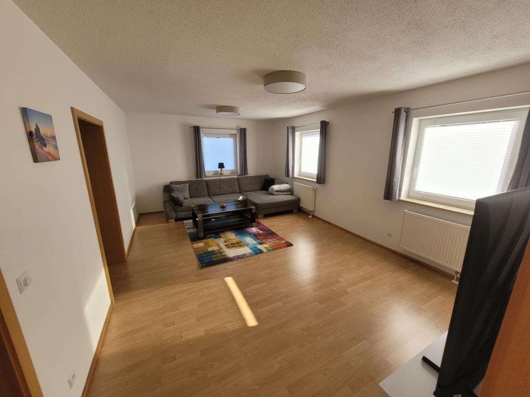 Living room with sofa, coffee table, and windows.