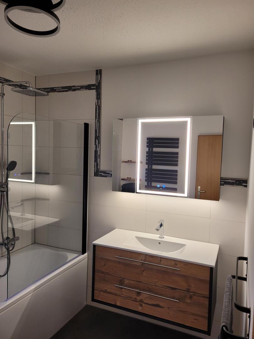 Bathroom with shower, sink, and illuminated mirror
