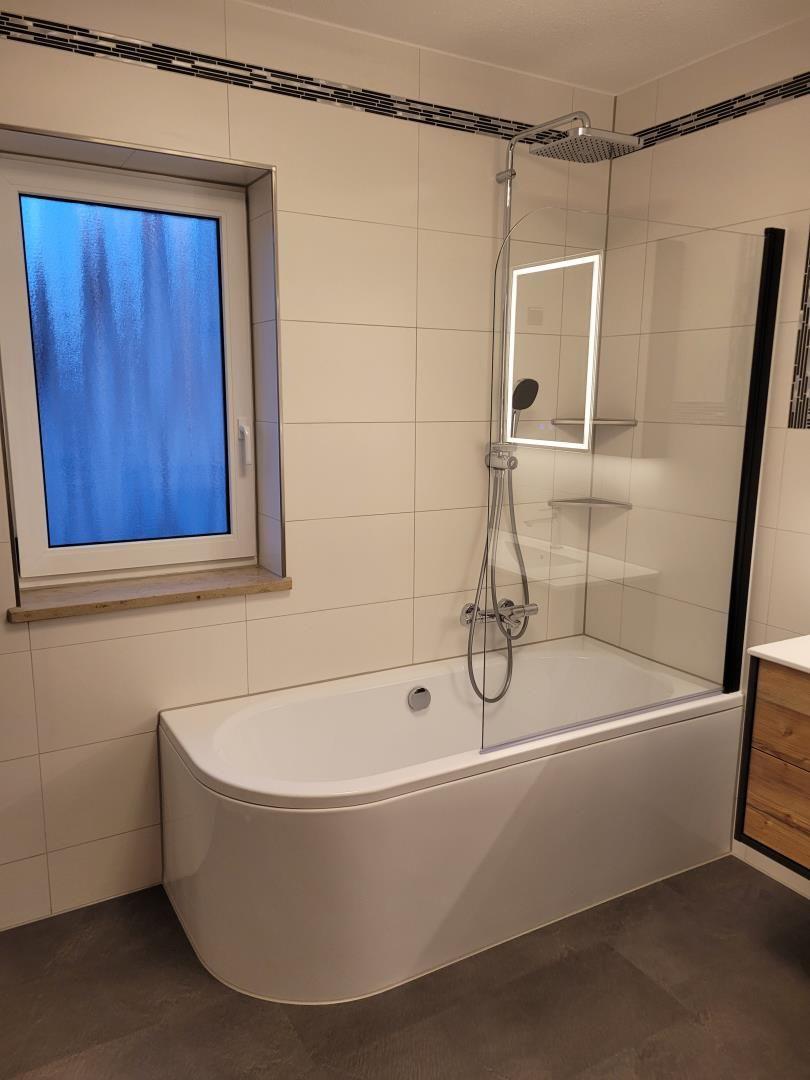 Bath with bathtub, shower, and window with blue glass.