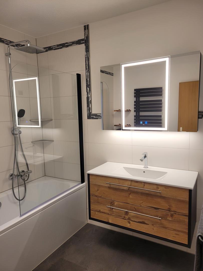 Bathroom with shower, sink, and illuminated mirror