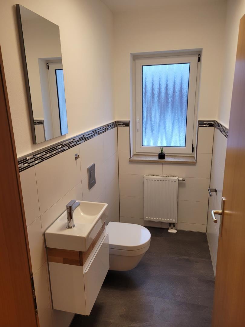 Bathroom with sink, toilet, and window with frosted glass.
