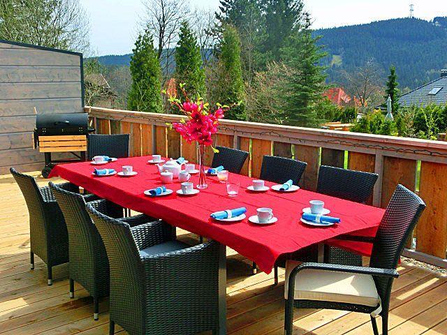 Terrasse mit gedecktem Esstisch, Grill und Bergblick.