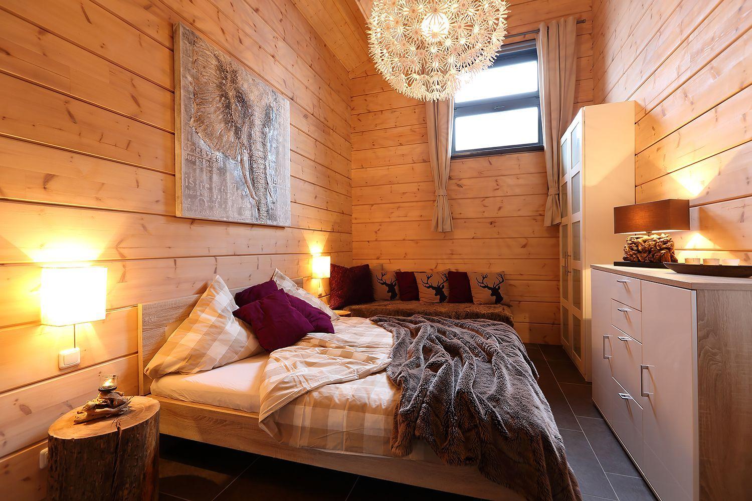 Schlafzimmer mit Holzwand, Bett, Nachttisch und Kleiderschrank.