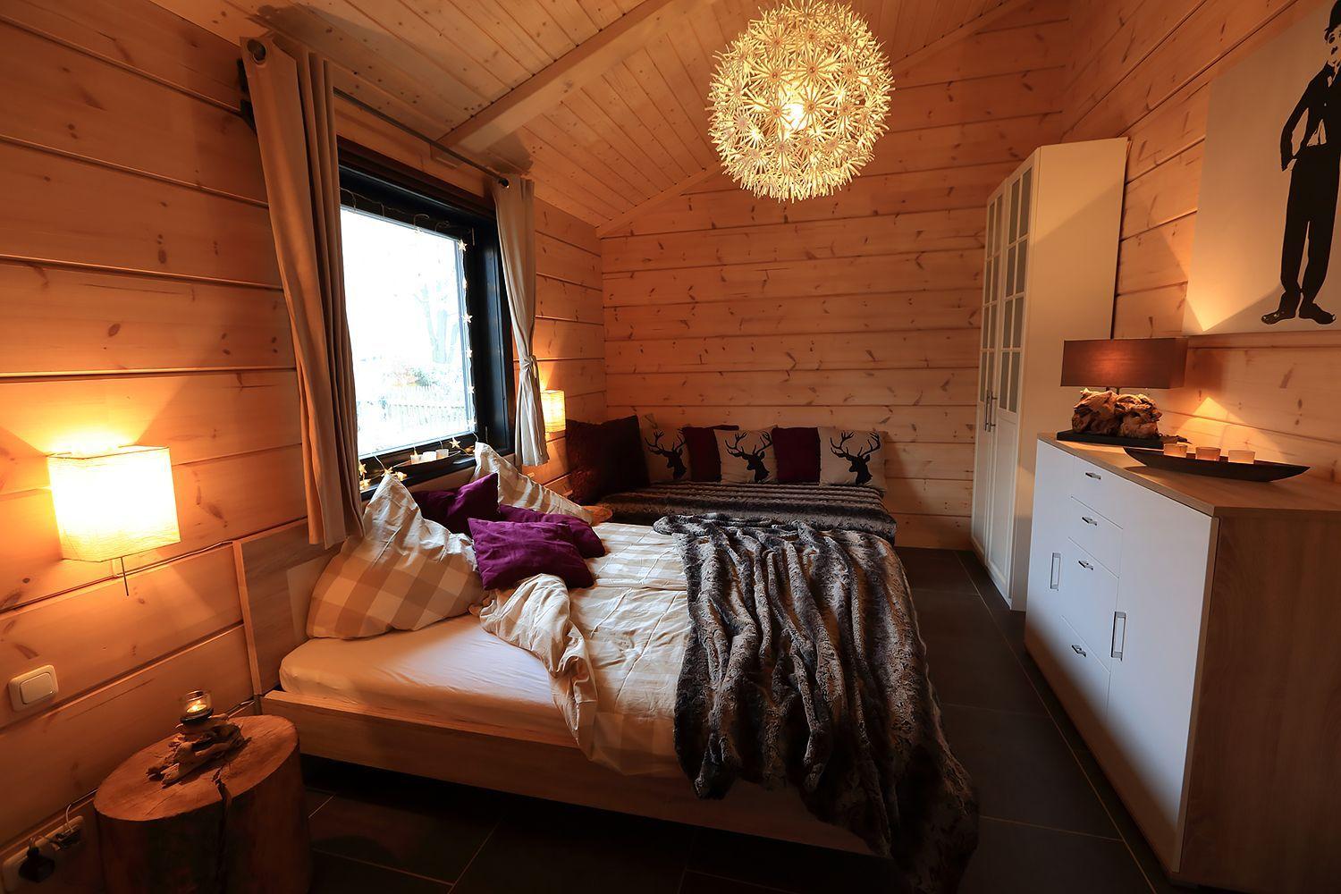 Schlafzimmer mit Holzwand, Bett, Fenster und Lampen.