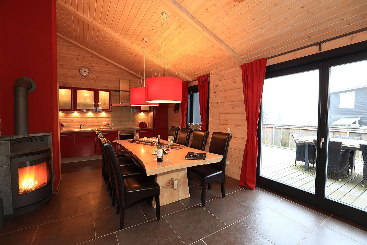 Essbereich mit Holztisch, schwarzen Stühlen und Kamin. Durchgang zur Küche und Terrasse.