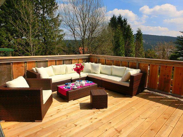 Terrasse mit Sitzgruppe, Tisch und Blick auf Wald und Berge.