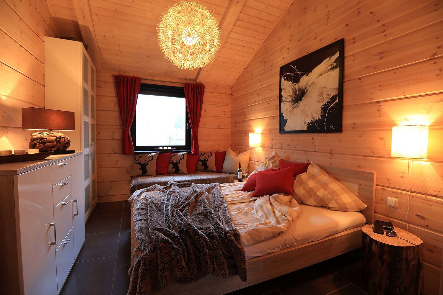 Schlafzimmer mit Holzwand, Bett, Fenster, Nachttisch und Decke.