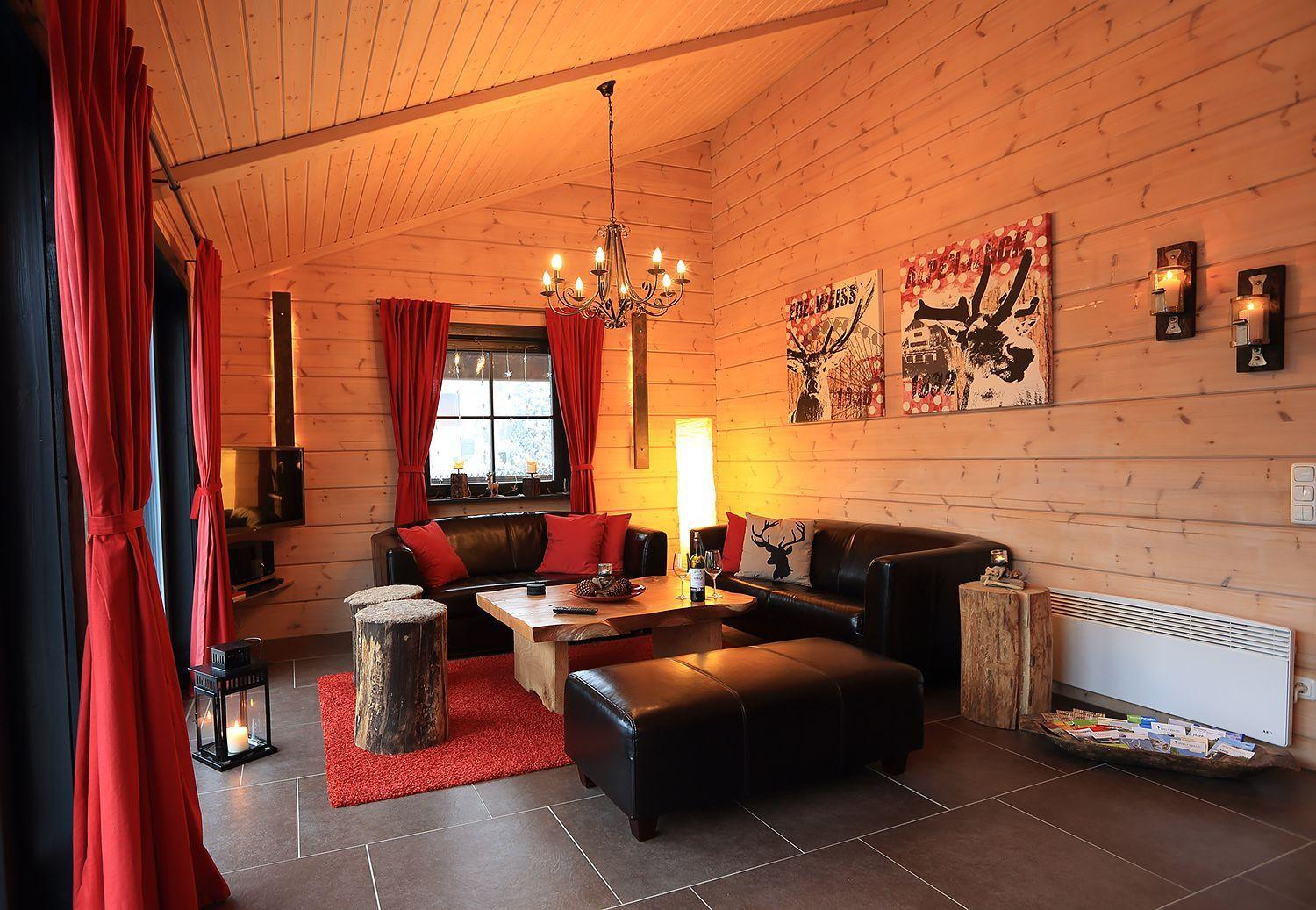 Wohnzimmer mit Holzwand, roten Vorhängen, Ledersofa und Holztisch.