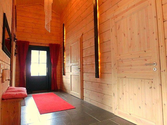 Holzgetäfeltes Foyer mit rotem Teppich, Tür und Wandlampen.