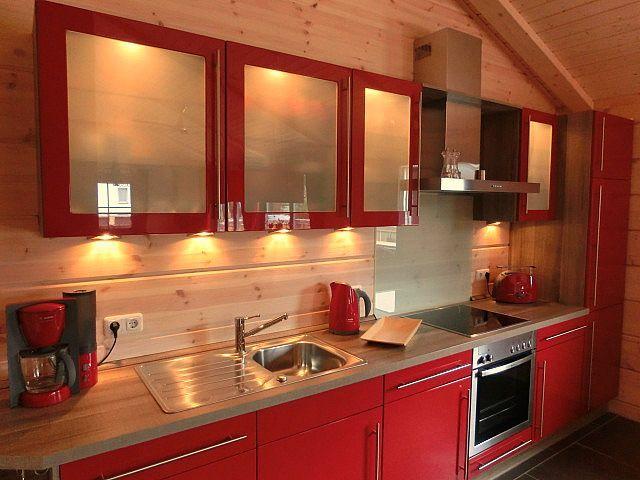 Küche mit roten Schränken, Edelstahlspüle und integriertem Herd.