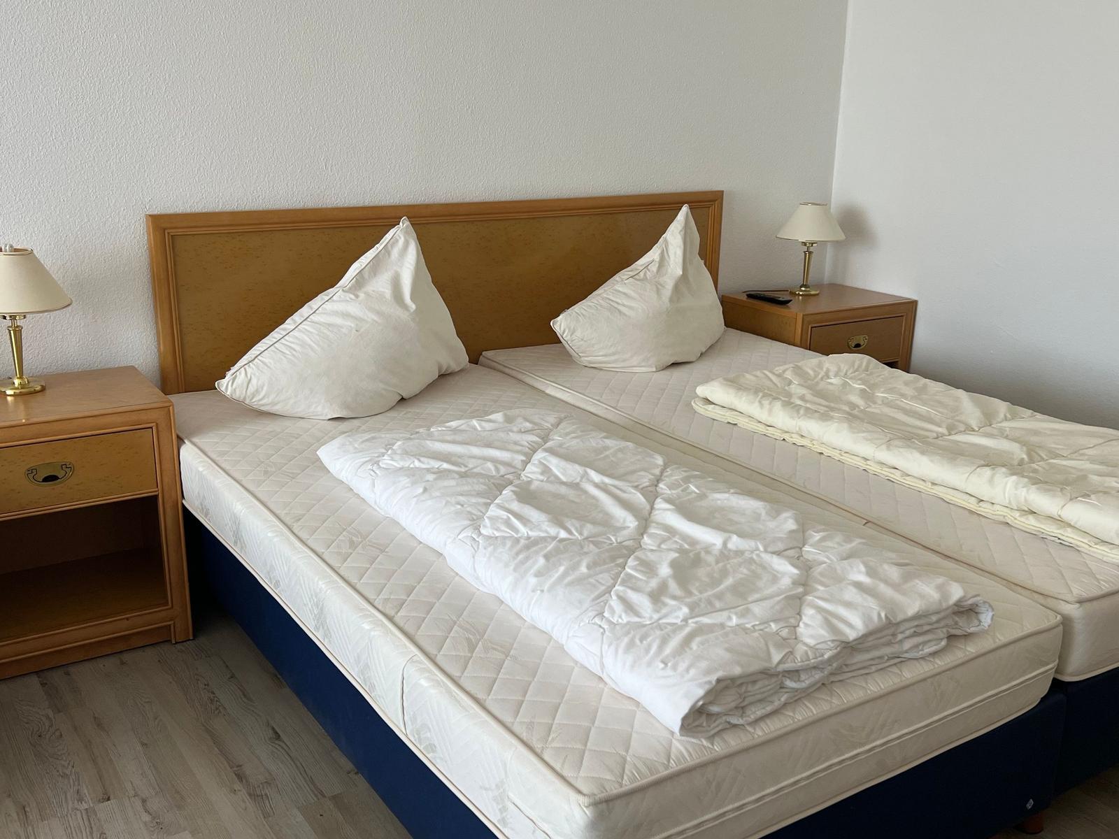 Zwei Einzelbetten mit weißen Bettwäsche und Nachttischen mit Lampen.